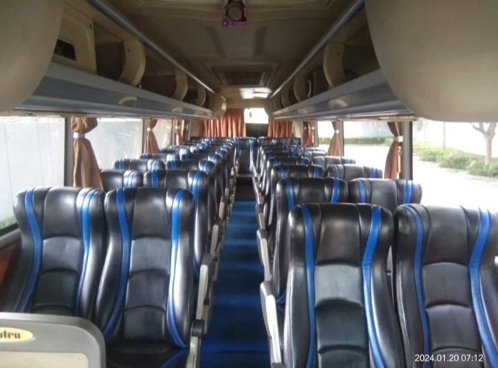 Interior big bus dengan deretan kursi kulit hitam bergaris biru